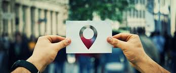 Mãos segurando cartão com ícone de localização em ambiente urbano